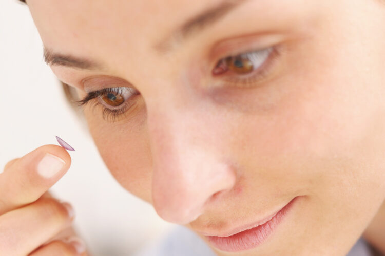 Frau setzt sich eine Kontaktlinse ein